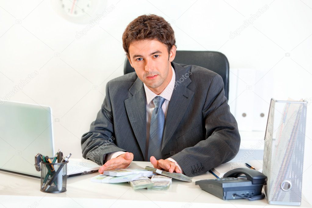 Modern businessman sitting at office desk and giving money packs
