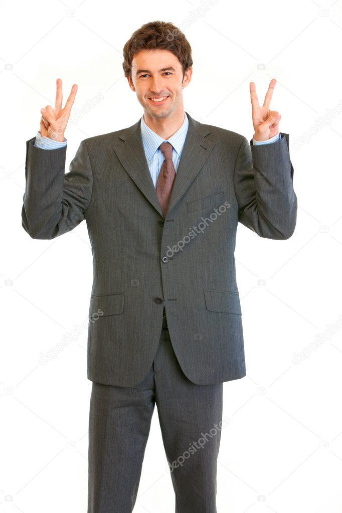 Pleased young businessman showing victory gesture