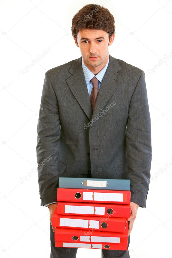 Stressful young businessman holding in hands heavy pile of folde