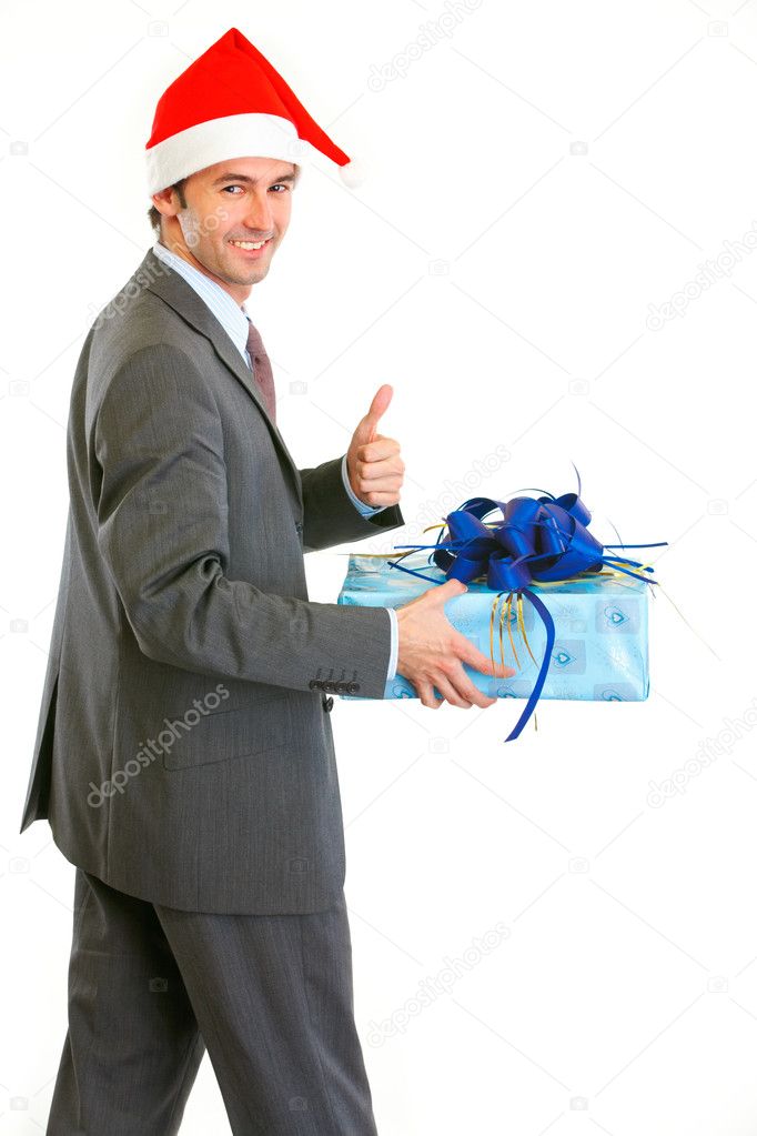 Happy modern businessman in Santa Hat holding present and showin