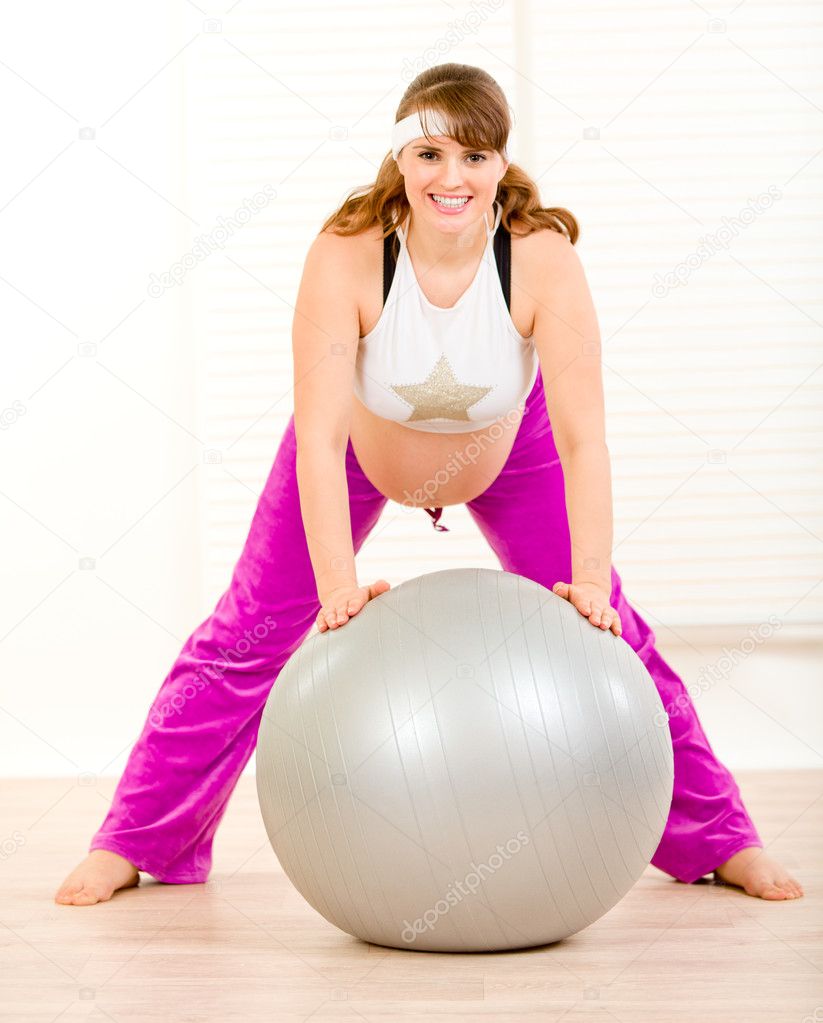 Pregnant female doing pilates exercises on gray ball