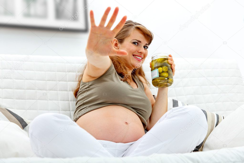 Embarrassed beautiful pregnant woman sitting on sofa