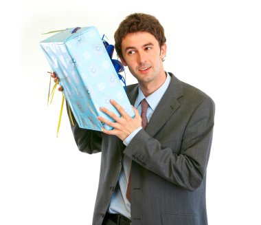 Modern businessman shaking present box trying to guess what's in clipart