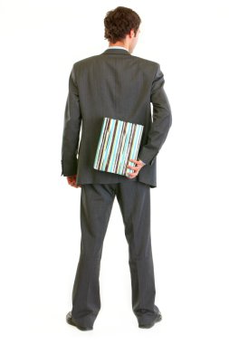 Modern businessman hiding present behind his back and standing b clipart