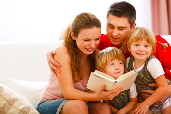 Pais felizes lendo para filhas gêmeas — Fotografia de Stock