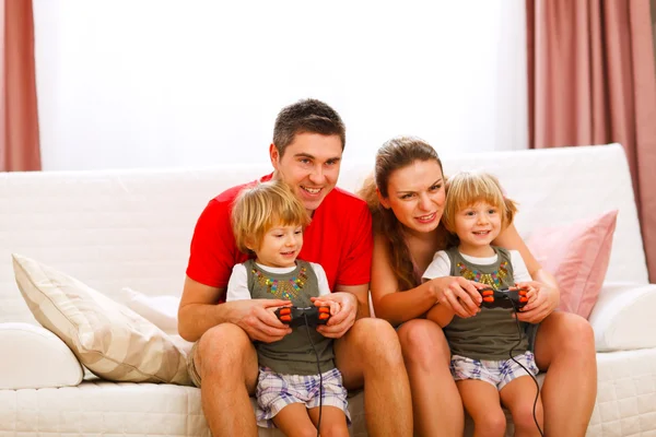 Mother and father playing with twins daughter on console — Stock Photo, Image