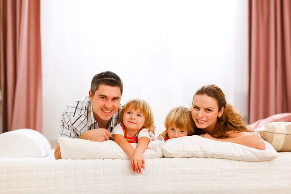 Семейный портрет матери отца и близнецов дочерей на кровати — стоковое фото
