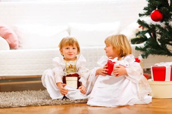 Dos lindos gemelos chica sentada con regalos cajas cerca de la Navidad t —  Fotos de Stock