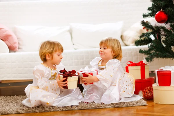 Zwei hübsche Zwillinge tauschen kurz vor Weihnachten Geschenke aus — Stockfoto