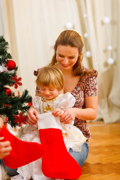 Moeder op zoek met dochter binnenkant van kerst sokken in de buurt van kiest — Stockfoto