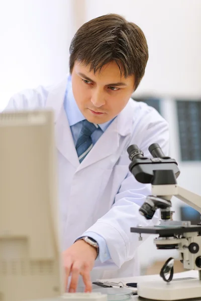 Investigador que trabaja en laboratorio médico utilizando microscopio y co —  Fotos de Stock