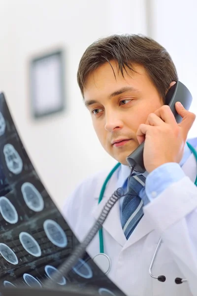 Médico segurando pacientes tomografia e falando telefone — Fotografia de Stock