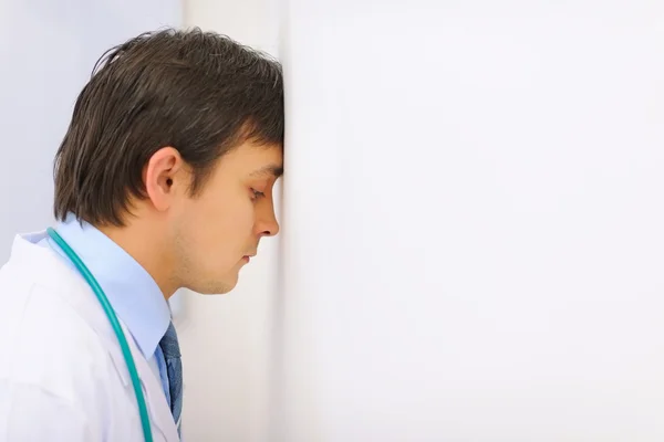 Tired medical doctor leaned his head into a wall — Stock Photo, Image