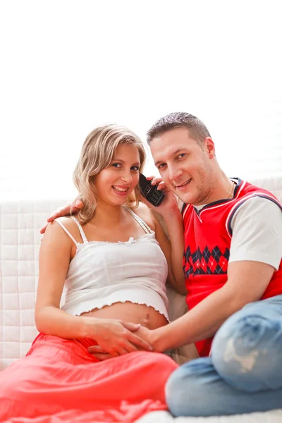 Glückliche schwangere Frau mit Mann, der Handy spricht — Stockfoto