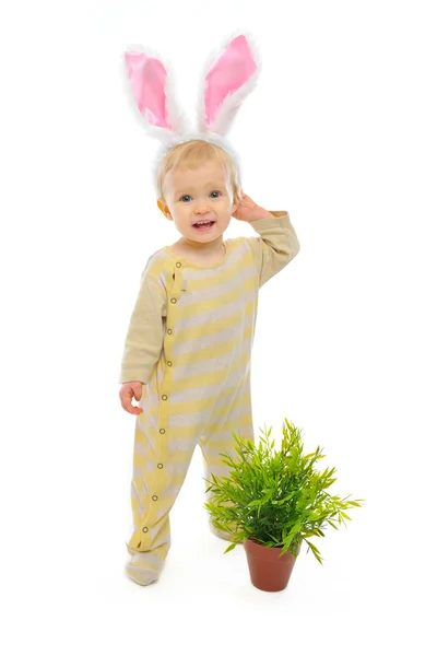 Милый малыш с кроличьими ушами, стоящий рядом с горшком с растительным изолятом — стоковое фото
