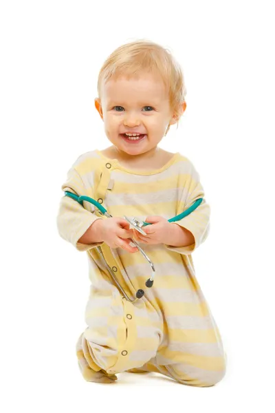 Happy baby with stethoscope sitting on floor isolated on white — Stock Photo, Image