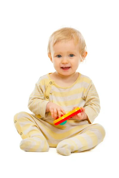 Adorable baby sitting on floor and playing with rattle isolated — Stock Photo, Image