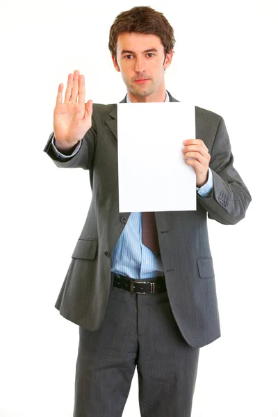 Серьезный современный бизнесмен держит чистую бумагу и показывает стоп — стоковое фото