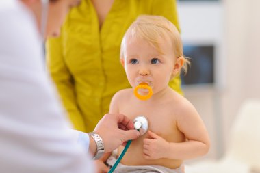 Baby being checked by pediatric doctor using stethoscope clipart