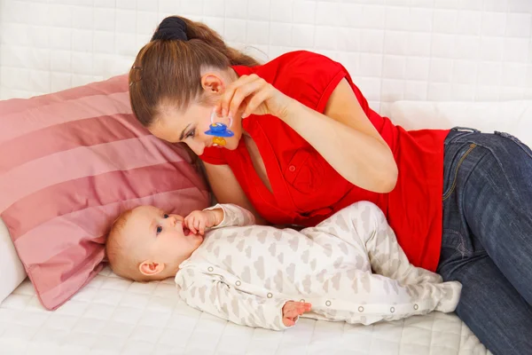 Young mother laying on sofa and playing with baby — Stock Photo, Image