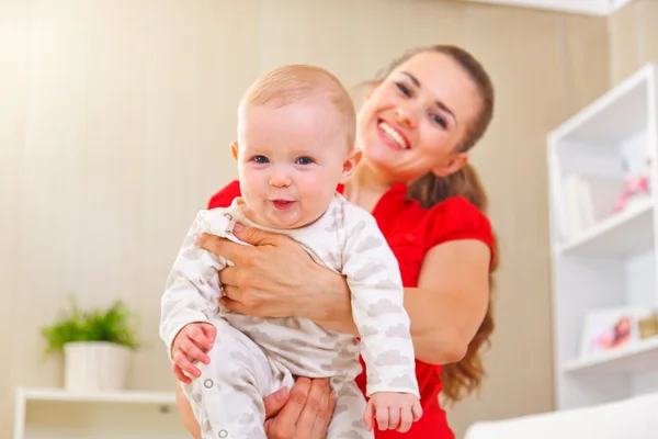 Lachende moeder en schattige baby spelen thuis — Stockfoto