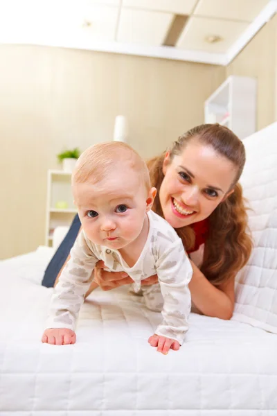 Happy mother and interested baby playing on divan — Stock Photo, Image