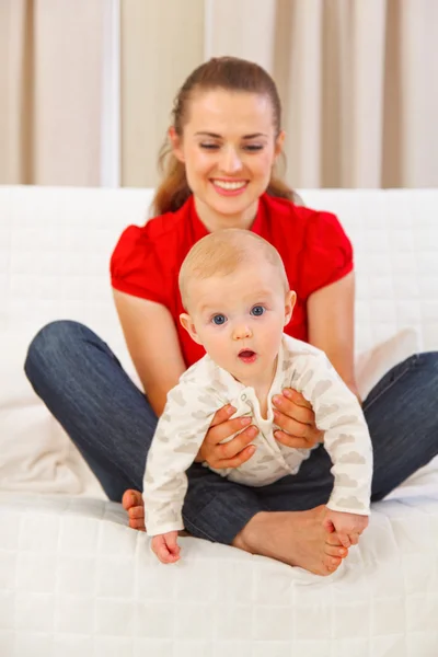 Interested baby playing on mothers laps — Stock Photo, Image