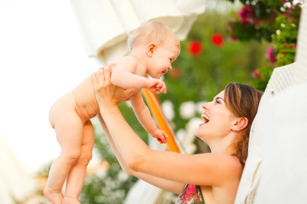 Gelukkig jonge moeder opleggen zonnebank en spelen met baby — Stockfoto