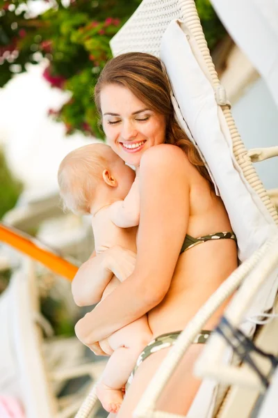 Glückliche junge Mutter liegt auf Sonnenbank und umarmt Baby — Stockfoto