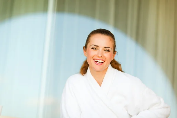 Portret van lachende jonge vrouw in badjas zittend op terras — Stockfoto