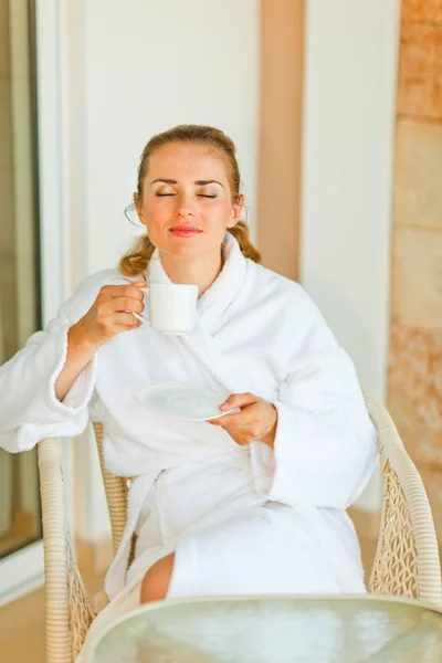Mujer joven en albornoz disfrutando de una taza de café en la terraza — Foto de Stock