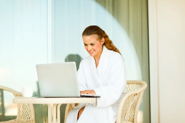 Gelukkig jonge vrouw in badjas zittend aan tafel op terras en u — Stockfoto