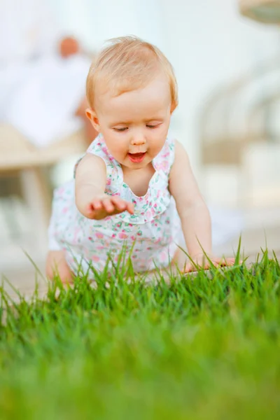 Szczęśliwe dziecko próbuje dotknąć trawa — Zdjęcie stockowe