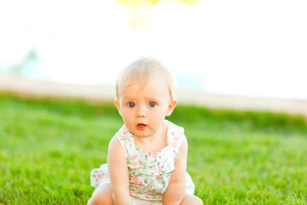 Portrait of interested baby sitting on grass — Stock Photo, Image