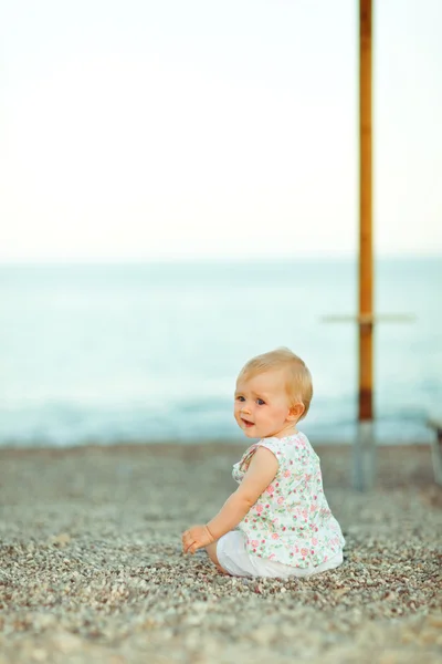Baby sitzt am Strand und blickt zurück — Stockfoto