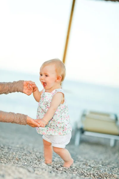 Boldog baba kipróbálás-hoz elkezd, séta a tengerparton anyák hel — Stock Fotó