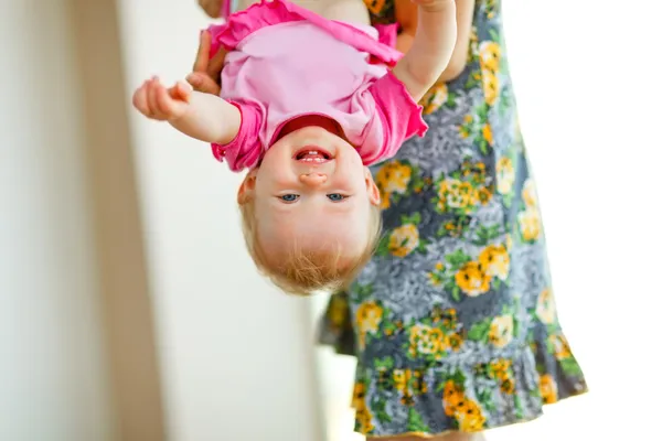 Mother holding smiling baby upside down — Stock Photo, Image
