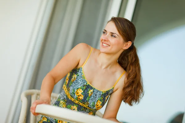 Mulher feliz sentado no terraço e olhando no canto — Fotografia de Stock