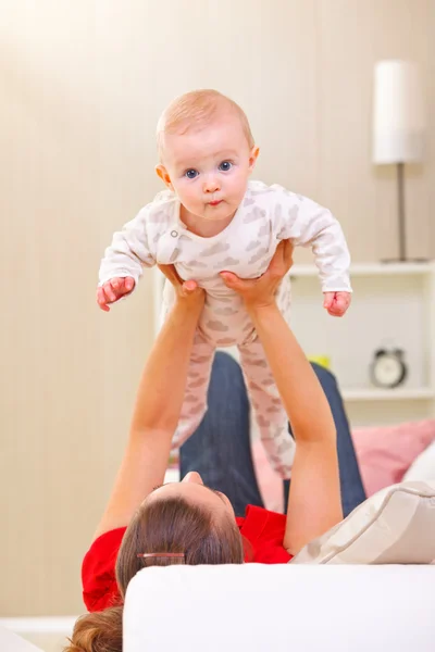 Baby spelen met moeder op divan — Stockfoto