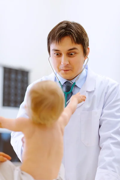 Médico pediátrico haciendo caras divertidas para el bebé en el examen —  Fotos de Stock