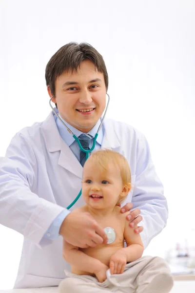 Médico pediátrico sorrindo verificando o bebê usando estetoscópio — Fotografia de Stock