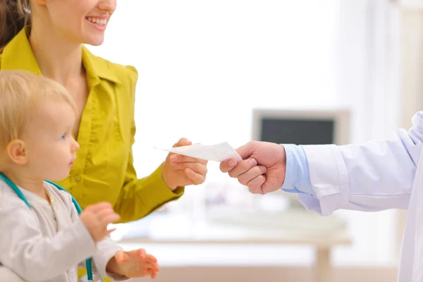 Closeup on pediatric doctors hand giving prescription to mother — Stock Photo, Image