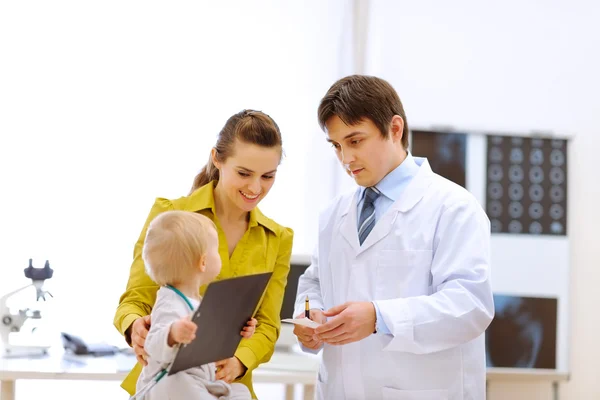 Pediatrician doctor explaining something to mother while baby pl — Stock Photo, Image