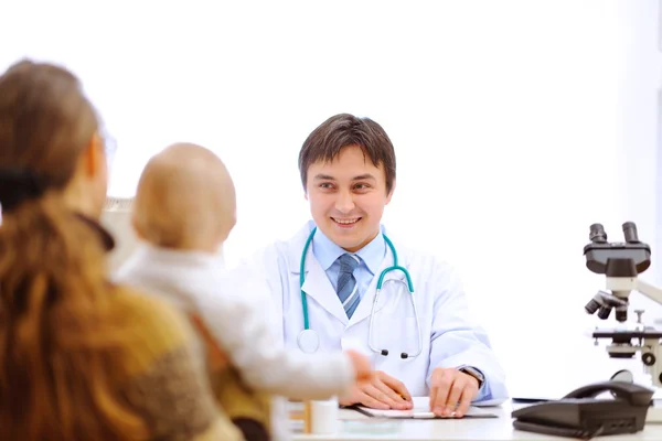 Pediatric doctor writing prescription to mother with baby — Stock Photo, Image