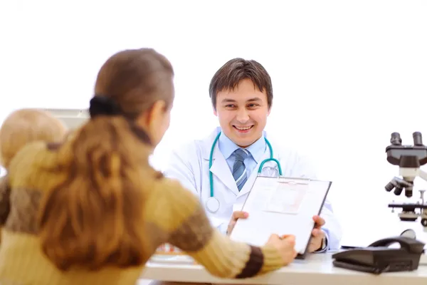 Pediatric doctor giving clipboard to sign to mother with baby — Stock Photo, Image