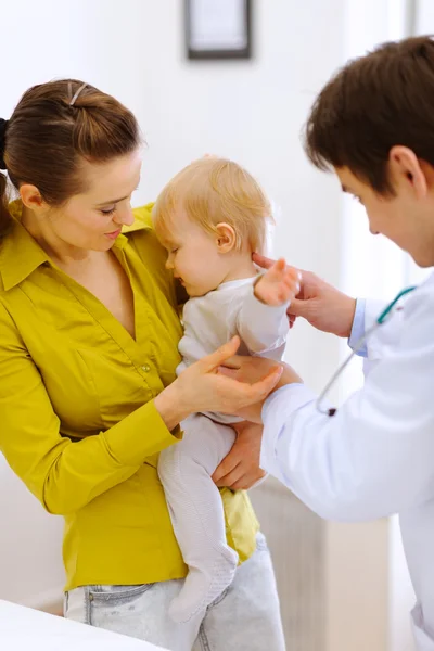 Scared baby on examination don't want to be checked by doctor Stock Picture