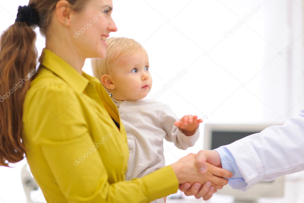Closeup on mother with baby thanking pediatrician doctor for exa