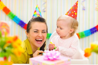 Happy mother celebrating first birthday of her baby clipart