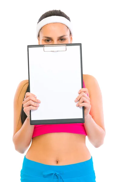Fitness girl hiding behind blank clipboard — Stock Photo, Image