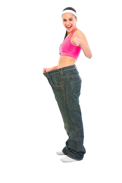Slim ragazza tirando jeans oversize e mostrando pollici in alto. Peso l — Foto Stock